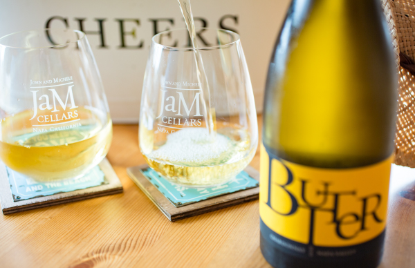 Two glasses of wine and bottle of JaM Cellars Butter with "Cheers" in the background