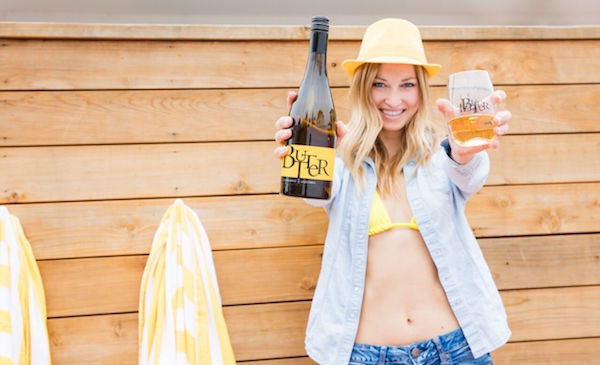 Woman in summer wear holding bottle and glass of JaM Cellars Butter