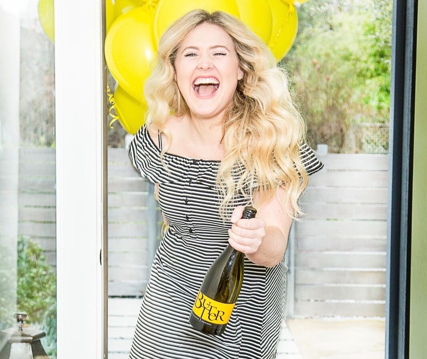 Woman holding JaM Cellars Butter with backdrop of yellow balloons