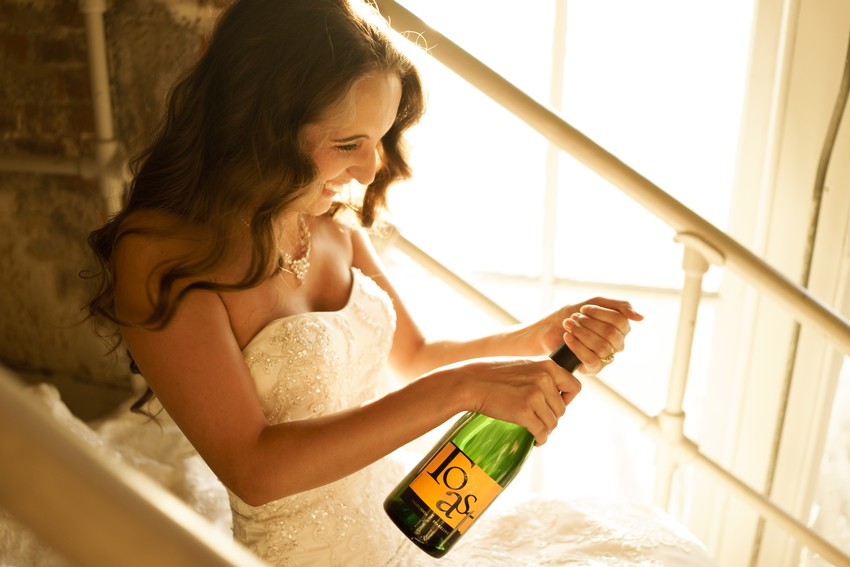 Woman in wedding dress opening a bottle of JaM Cellars wine