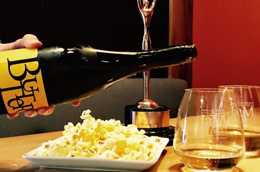 Pouring bottle of JaM Cellars Butter into glasses with popcorn in background