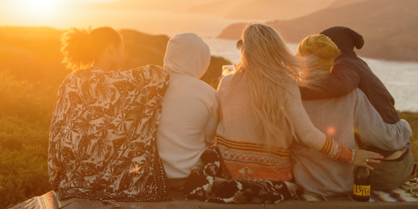 Five people sitting in a row at sunset asking, "What happened to our extra Happy Hour?"