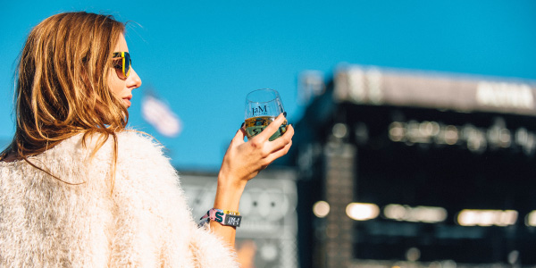 Woman in faux fur with glass of JaM Cellars wine