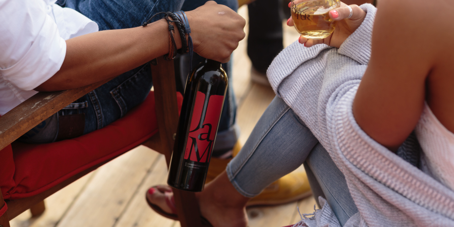 Two people sitting on deck chairs enjoying JaM Cellars wine