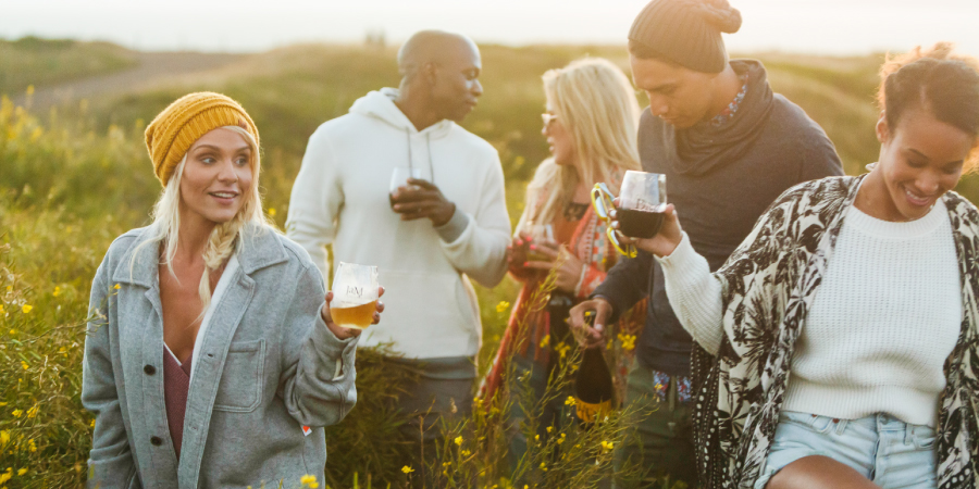 People in a field enjoying glasses of JaM Cellars wine