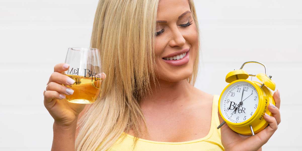 Woman holding yellow alarm clock and glass of JaM Cellars Butter wine
