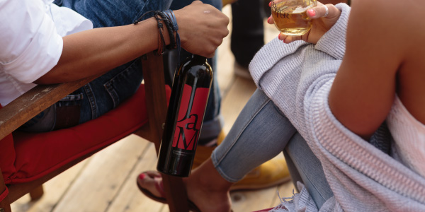 Two people enjoying JaM Cellars wine sitting on lawn chairs on deck