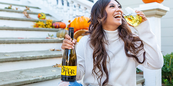 Woman with bottle of JaM Cellars Butter wine against a backdrop of pumpkins on stairs